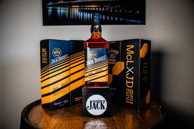 2024 Jack Daniel's x McLaren collaboration bottle with '24 and '23 boxes in background, lit by LED mounted underneath the bottle